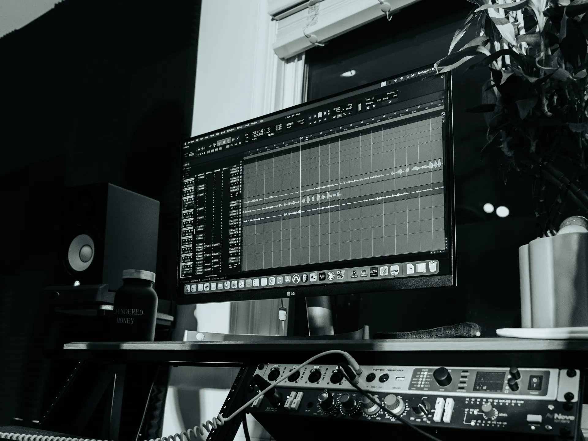 The studio desk from low: a session open on the screen, the interface in front, monitors either side.