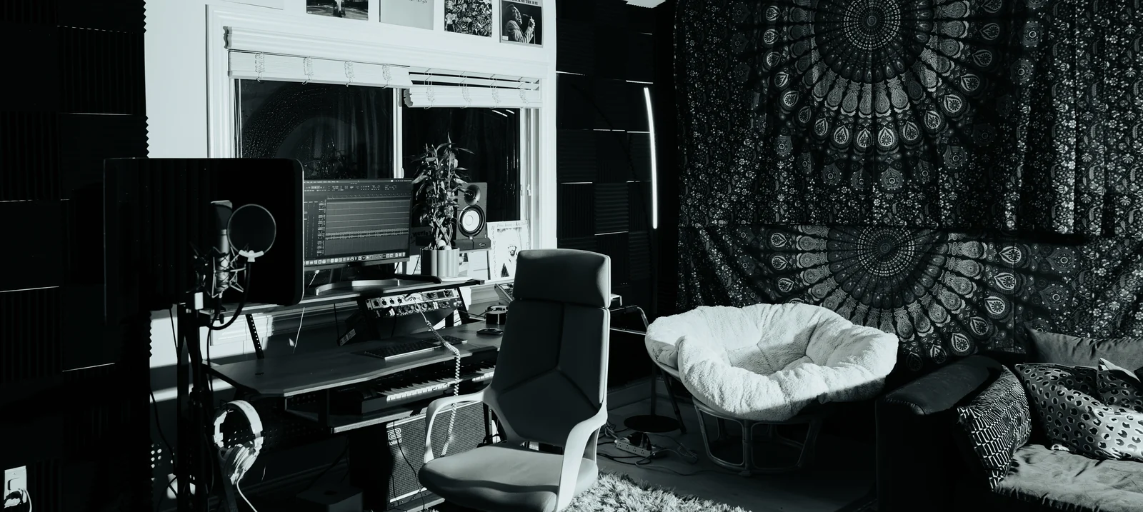The live room: foam-treated walls, the desk and monitors, chairs and a tapestry.